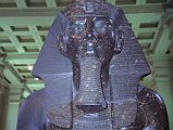 British Museum Top 20 19-2 Amenophis III Seated Statue Close Up 19. Amenophis III Seated Statue, Thebes Egypt, about 1400BC. In room 4 there are two 3m high seated statues in black granite of Amenophis III (also spelled Amenhotep). Amenhophis III was the first Egyptian King to be worshipped as a god in his own lifetime. Here is a close up of the head of the other statue, with a head-dress ornamented in front with a Uraeus, the figure of the sacred serpent that was an emblem of sovereignty.